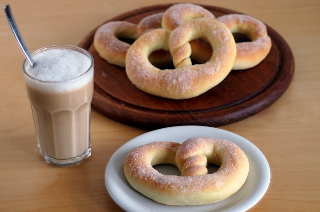 Martinsbrezel, eine süße Brezel aus Hefeteig, serviert mit einem Milchkaffee