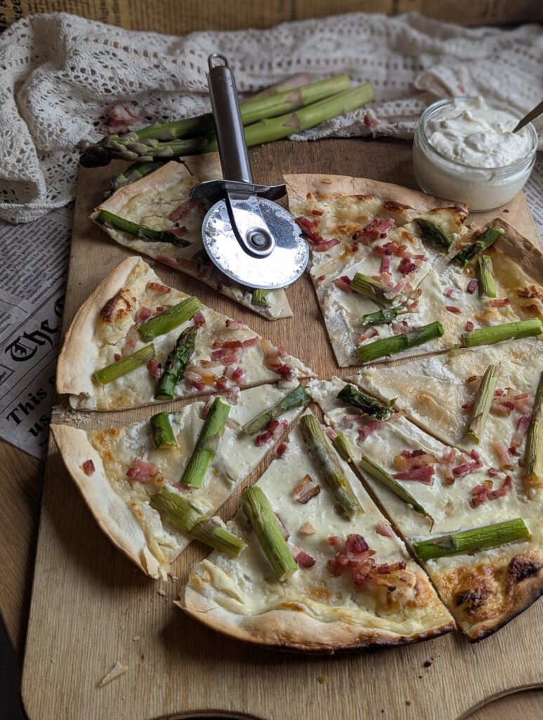 auf einem Holzbrett liegt ein runder Spargel-Flammkuchen