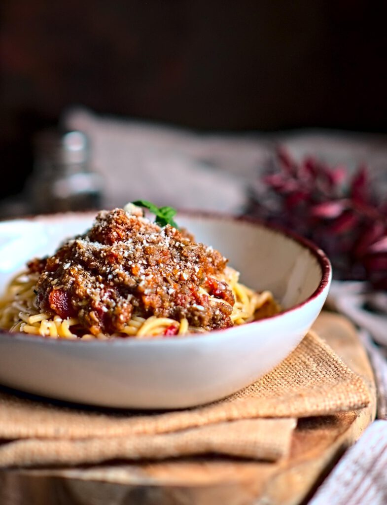 bräunliche Veggie Bolognese aus Pilzen auf Spaghetti mit Hartkäse in einem tiefen Teller serviert