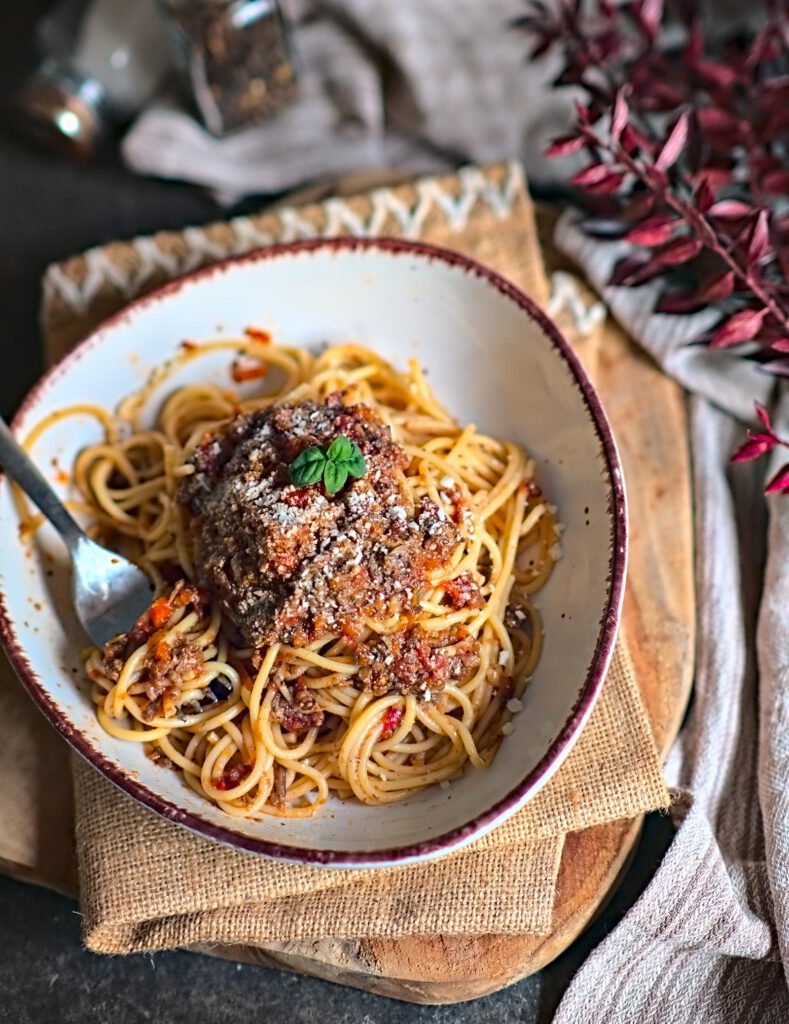 sämige Veggie Bolognese Soße vermischt mit Spaghetti und Hartkäse im tiefen Teller