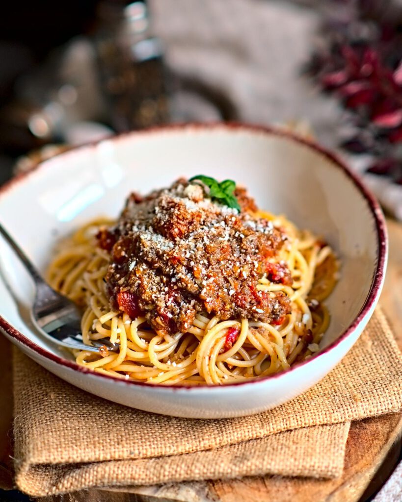 Nahaufnahme von Spaghetti mit sämiger Veggie Pilz Bolognese in einem tiefen Teller