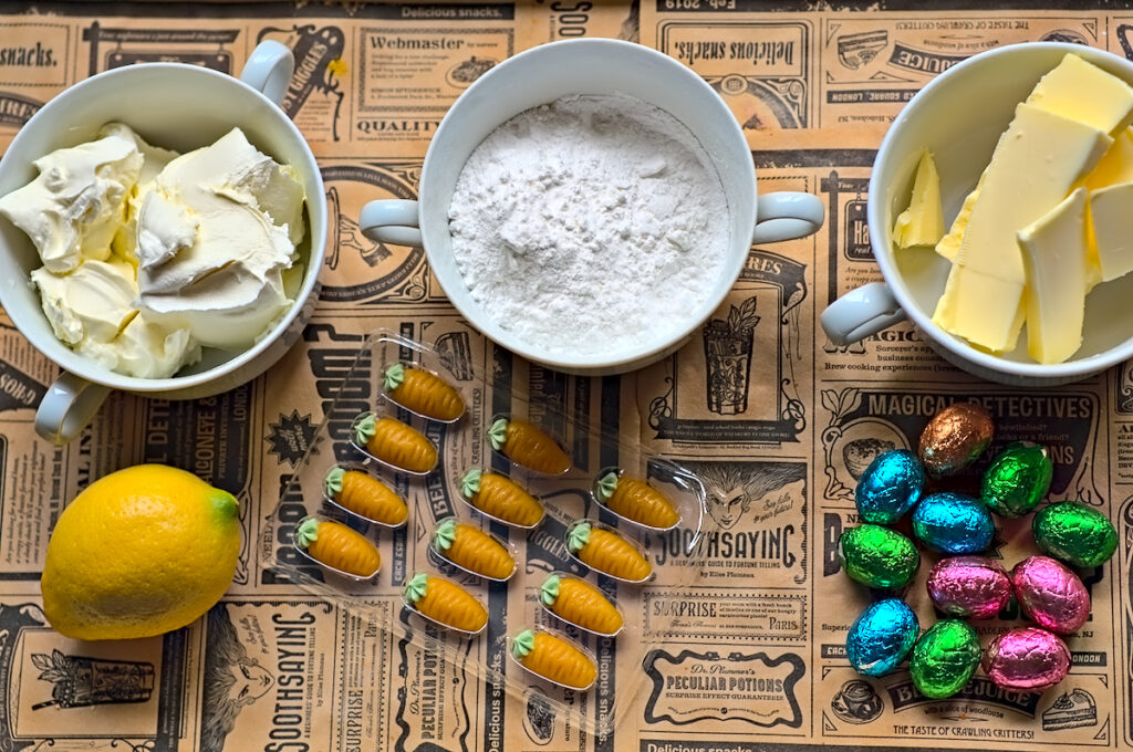 Frischkäse, Puderzucker, Butter, Schokoeier, Marzipan Möhrchen und Zitrone als Zutaten für das Frischkäsefrosting auf dem Rübli Blechkuchen