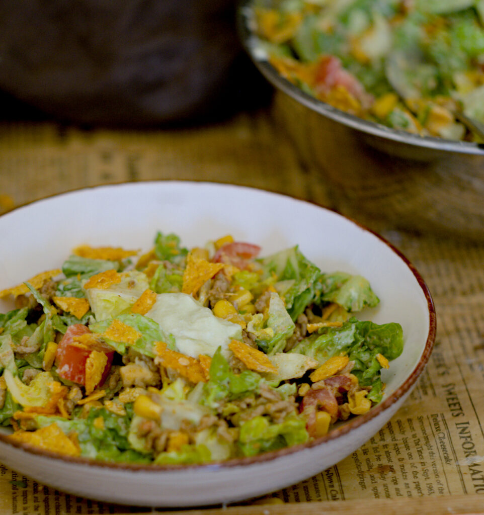 eine Schüssel mit leckerem Taco-Salat und Dressing befindet sich auf diesem Bild