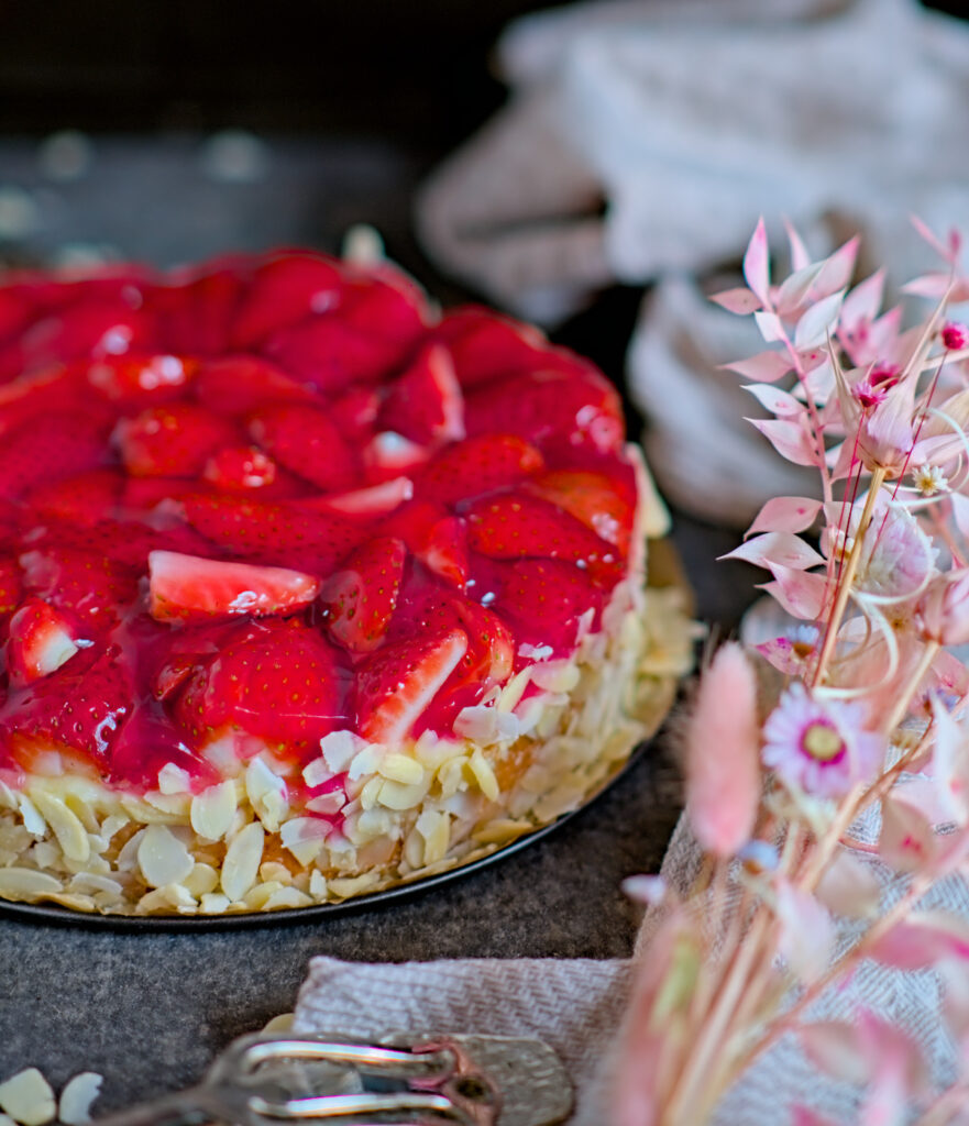 Detailansicht Erdbeerkuchen mit Vanillepudding mit Mandelblättern verziert auf einer Schieferplatte