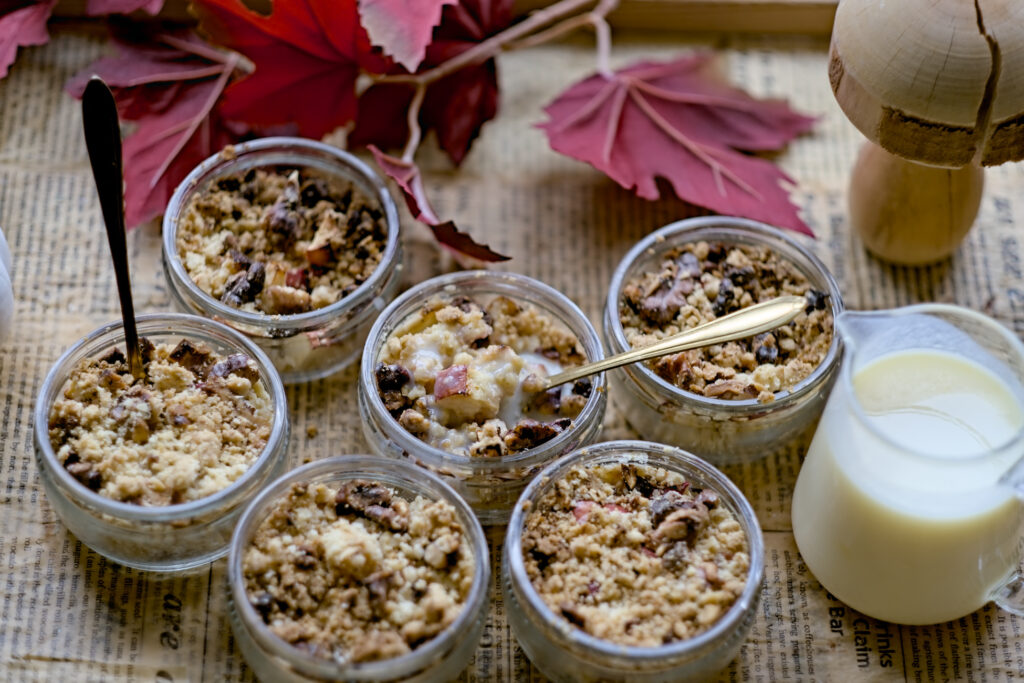 6 Gläser gefüllt mit Apfelkuchen und Crumble sind auf dem Bild zu sehen. Vanillesoße steht daneben. Ein Airfryer Rezept