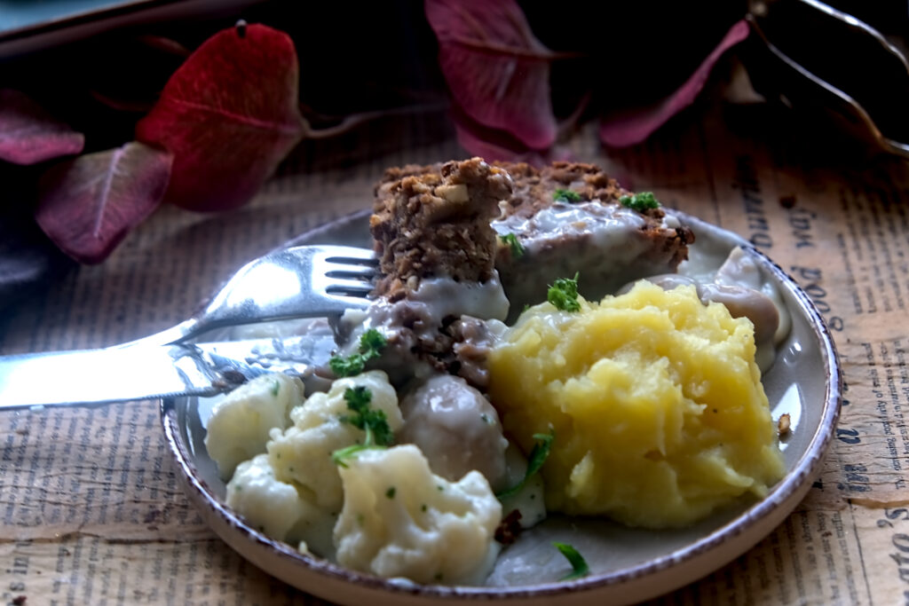 auf einem weißen Teller liegt ein Stück Linsenbraten mit Blumenkohl und Kartoffelpüree