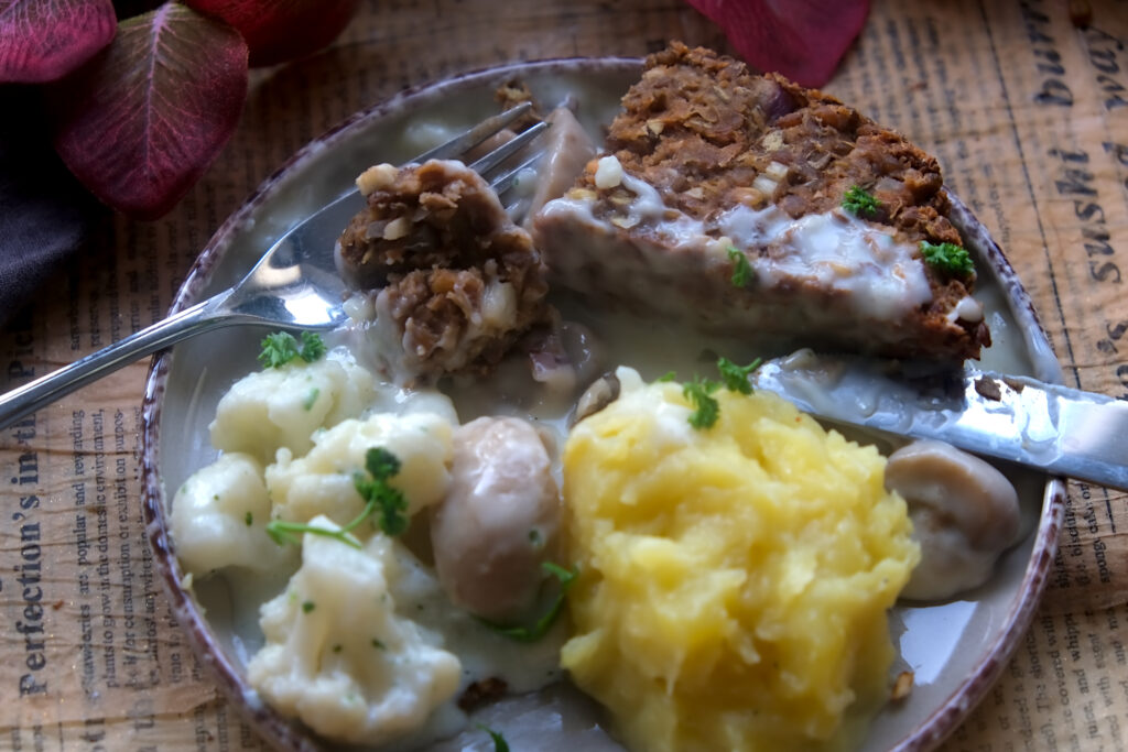 auf einem weißen Teller liegt ein Stück Linsenbraten mit Blumenkohl und Kartoffelpüree