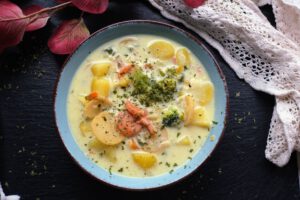 eine blaue Schüssel mit Gemüsesuppe und Kräutern