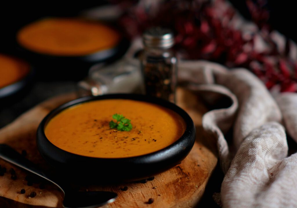 Gemüsecremesuppe in einer Schüssel mit Kräutern und Pfeffer