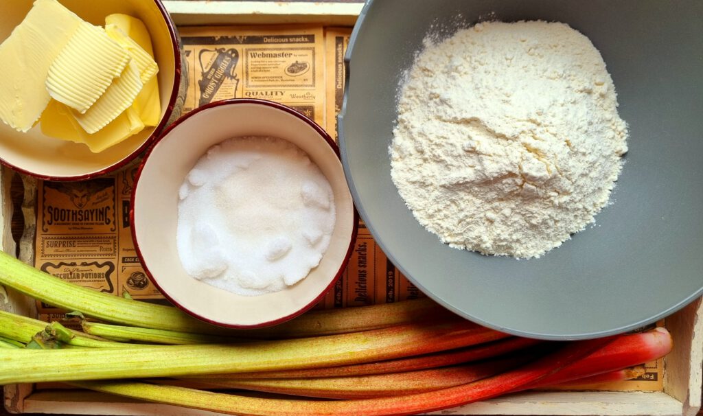 Zutaten für Rhabarber-Streuselkuchen: Butter, Puderzucker, Mehl, Vanillezucker, Rhabarber, eventuell Zimt