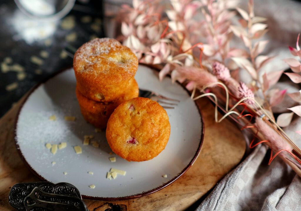 drei goldbraune Muffins mit Rhabarberstückchen auf einem Teller