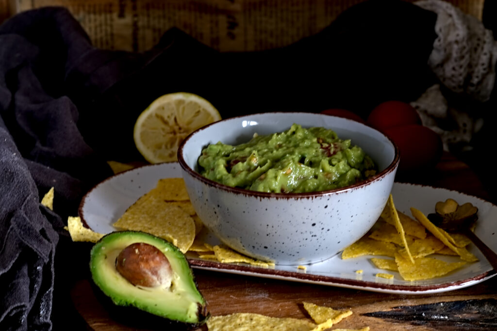 auf dem Bild sieht man eine Schüssel mit Guacamole, mit Tacos, Avocado und Zitrone