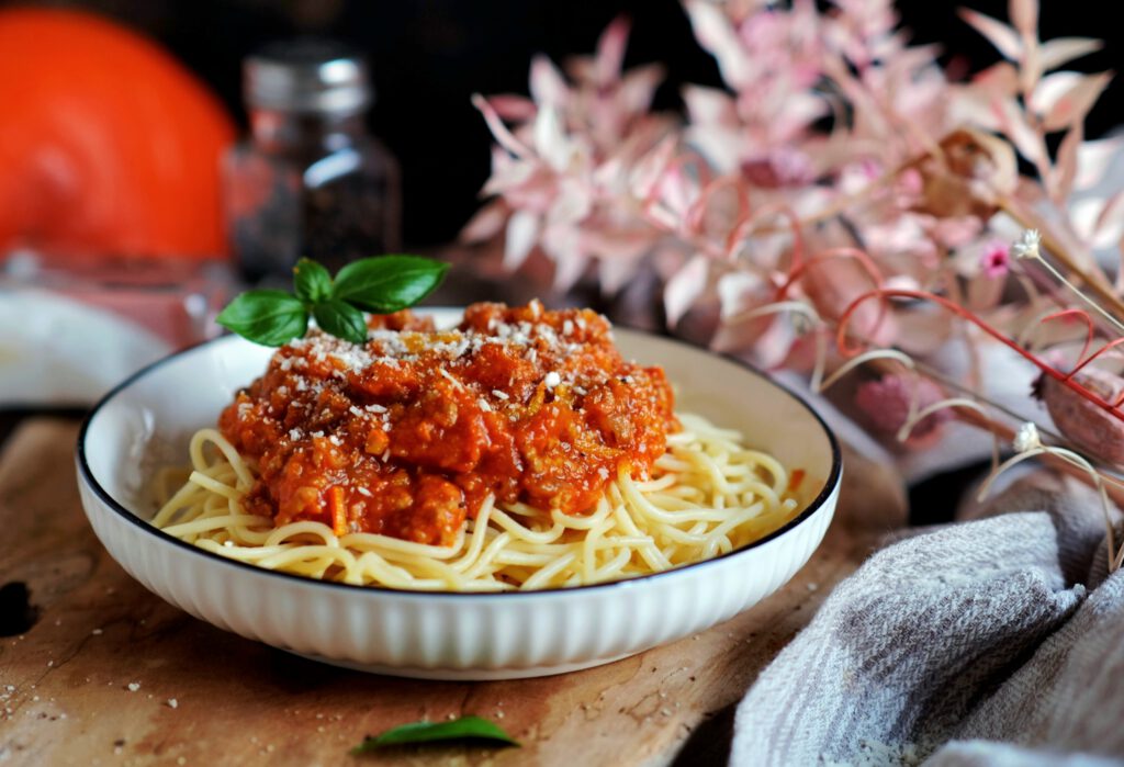 Eine Schüssel mit Penne, bedeckt mit einer orangefarbenen Kürbis-Hackfleisch-Sauce