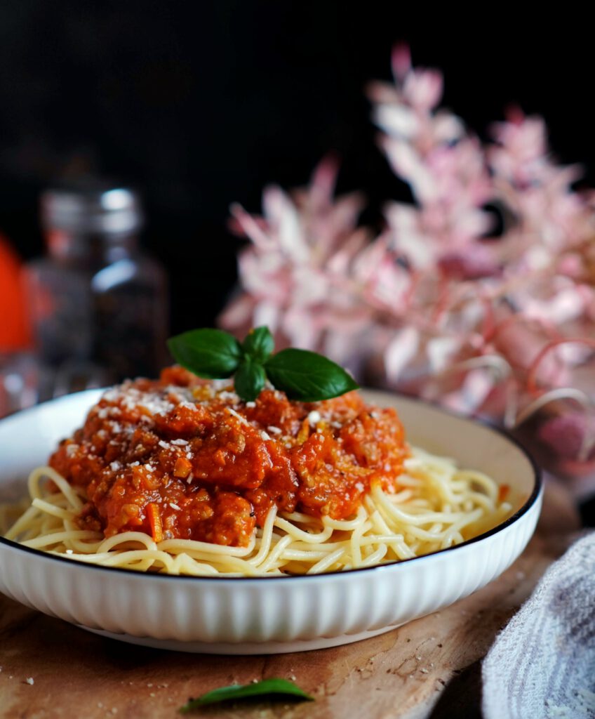 Nahaufnahme von Kürbisbolognese, garniert mit Parmesan und frischer Petersilie