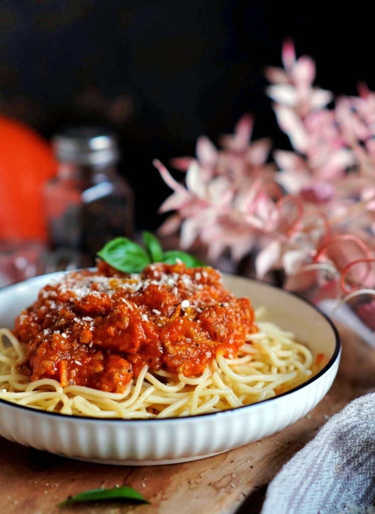 Ein rustikaler Keramikteller mit einer großzügigen Portion Kürbisbolognese