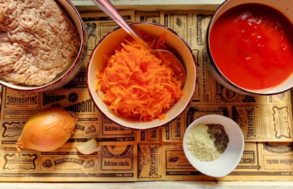 Zutaten für die Kürbisbolognese: Zwiebeln, Knoblauch, geriebener Kürbis, passierte Tomaten, Hackfleisch, Gewürze