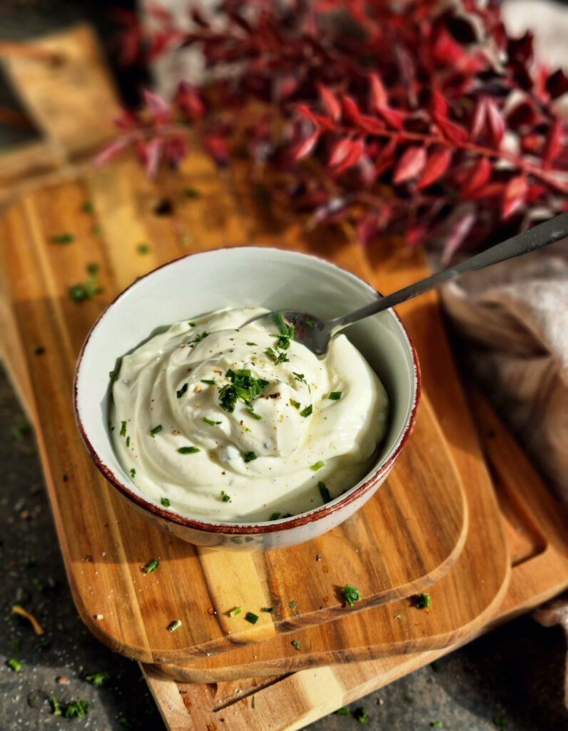 Nahaufnahme von einem Löffel, der in einer Schale Sour Cream Dip steckt