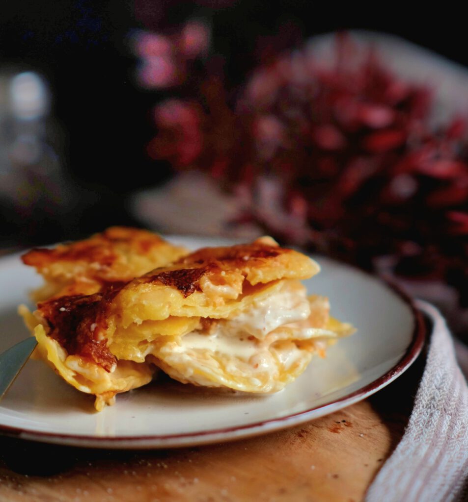 Portion cremiges Kartoffelgratin auf einem Teller als perfekte Beilage zu Fleisch