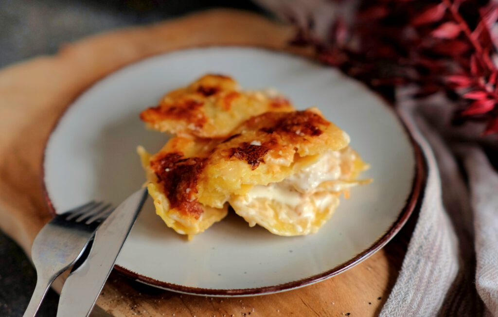 eine Portion cremiges Kartoffelgratin auf einem Teller