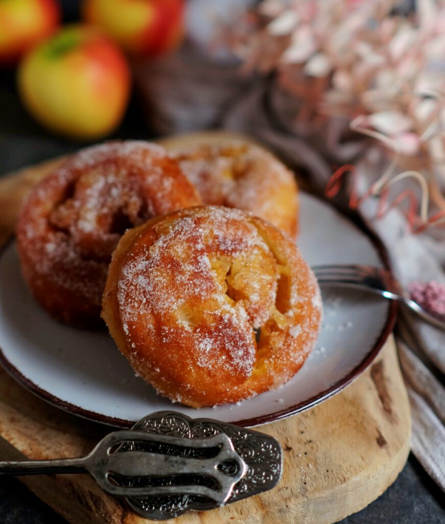 frittierte Apfelberliner auf einem Teller, frisch in Zimt und Zucker gewälzt