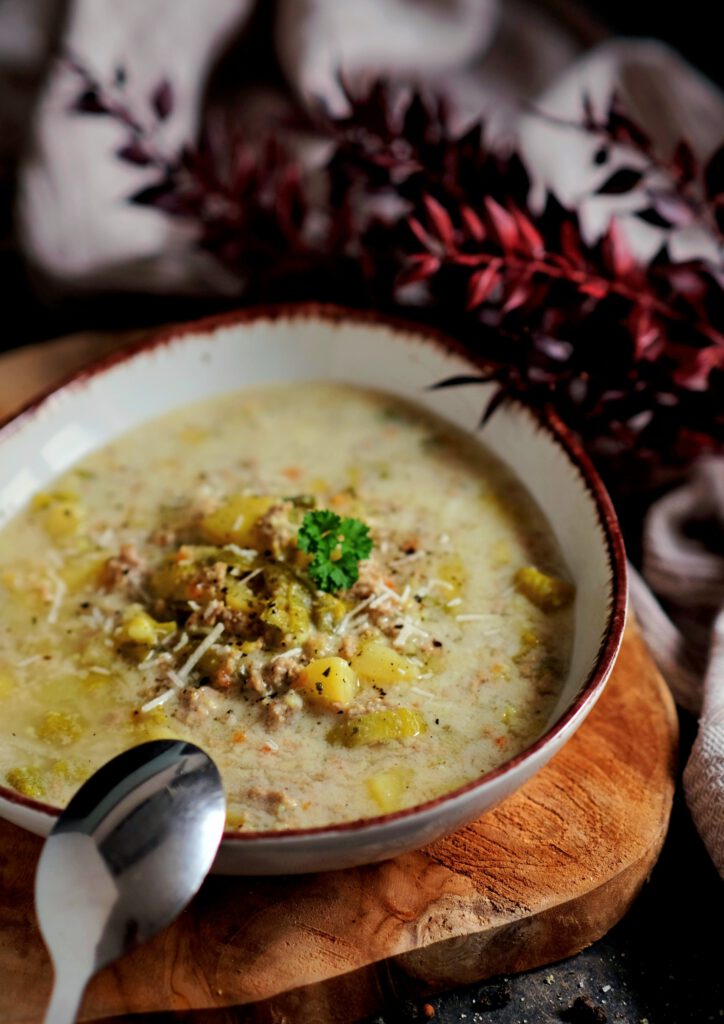 Ein Löffel der sämigen Käse-Lauch-Suppe mit viel Hackfleisch und Lauchringen.