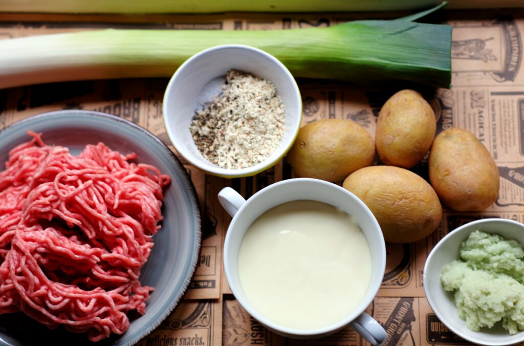 Zutaten der Käse-Lauch-Suppe: Zwiebeln, Knoblauch, Kartoffeln, Hackfleisch, Porree, Schmelzkäse, Gewürze