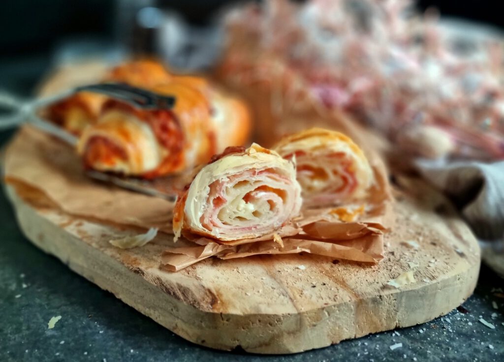 Ein aufgeschnittenes Croissant mit saftigem Schinken und einer dicken Schicht geschmolzenem Käse