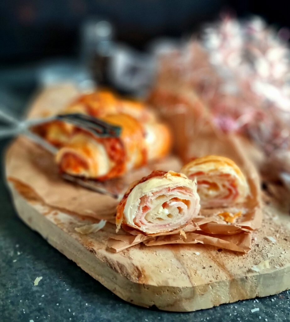 Ein glänzendes, blättriges Buttercroissant gefüllt mit einer Scheibe Kochschinken und Käse