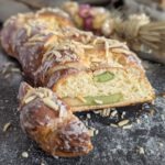 Marzipan Zopf der auf einer schwarzen Unterlage liegt. im Hintergrund befinden sich Trockenblumen