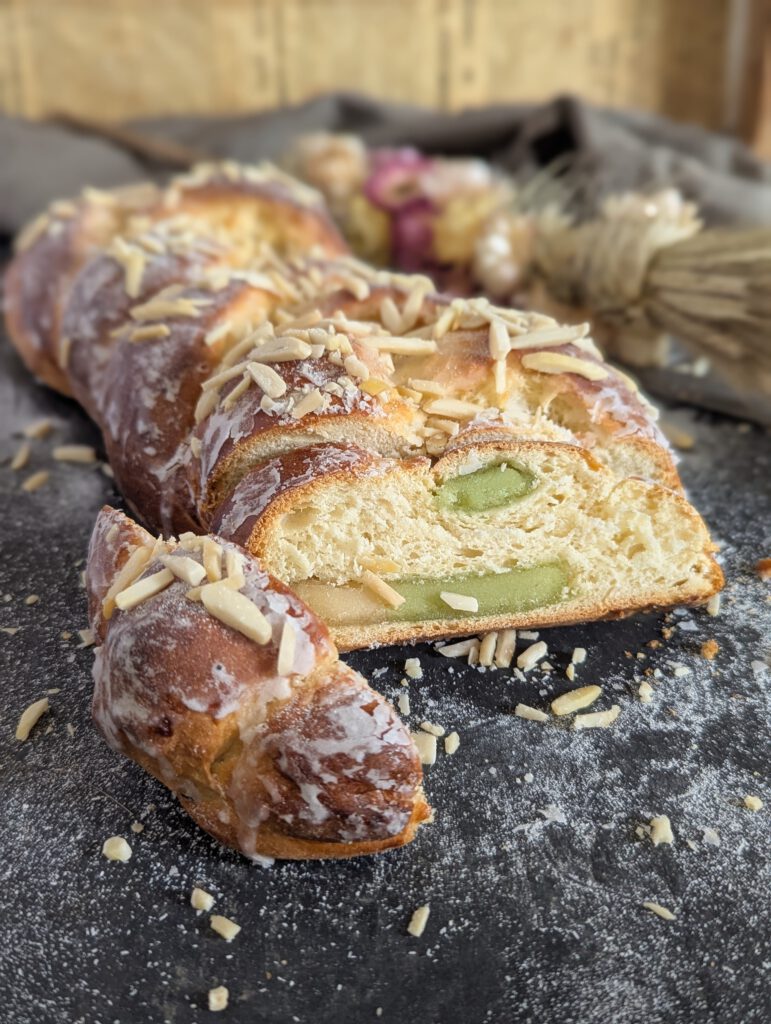 Marzipan Zopf der auf einer schwarzen Unterlage liegt. im Hintergrund befinden sich Trockenblumen
