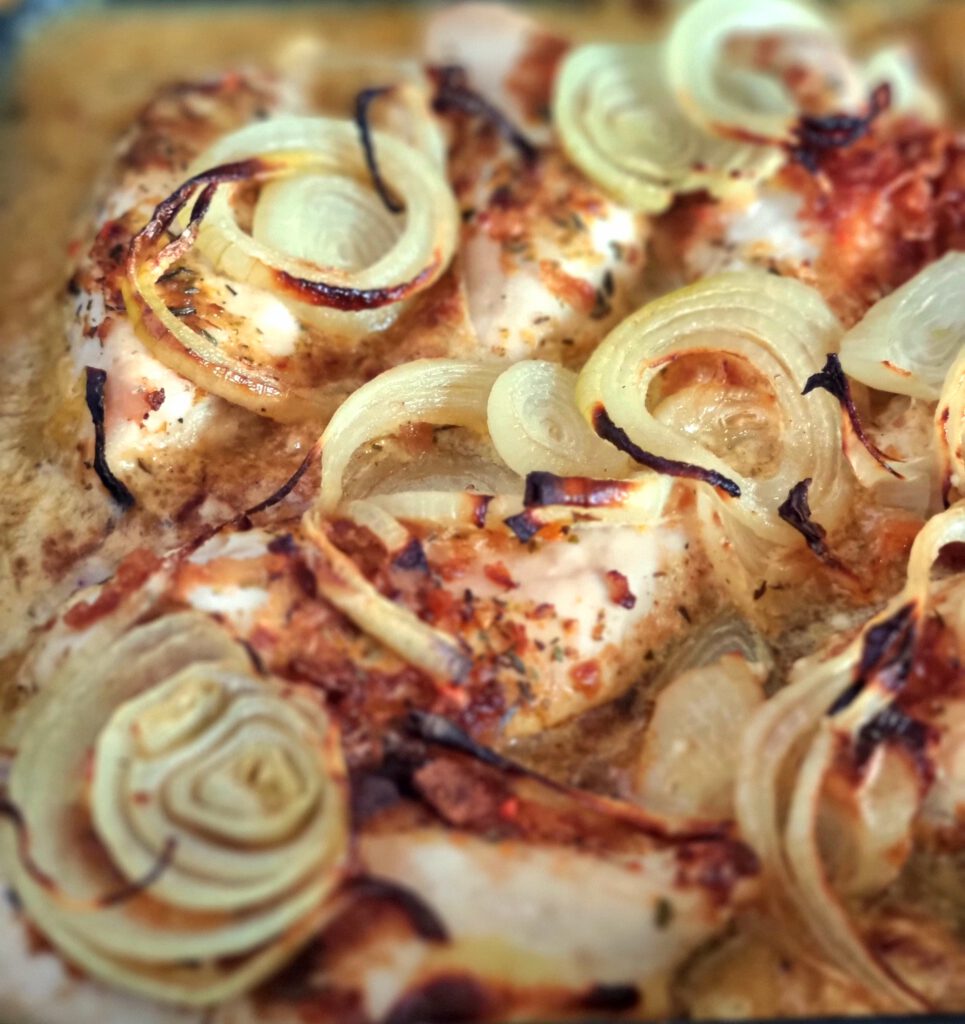Eine Nahaufnahme von unserem Zwiebel-Sahne-Hähnchen. Goldbraun gebacken mit Zwiebelringen