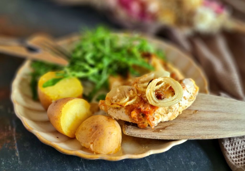 Zwiebel-Sahne Hähnchen mit Kartoffeln und Salat auf einem Tellere