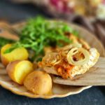Zwiebel-Sahne Hähnchen mit Kartoffeln und Salat auf einem Tellere