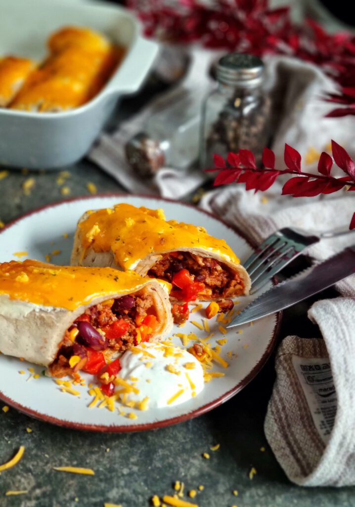 würzige Hackfleisch-Enchiladas aus weichen Weizen-Wraps, herzhaft überbacken mit geriebenem Cheddar. Auf der warmen Portion schmilzt ein großzügiger Klecks cremiger Schmand.