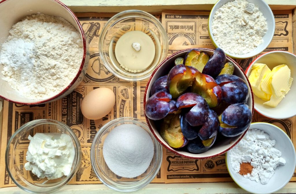 Zutaten für schnellen Zwetschgenkuchen mit Quark-Öl-Teig und Streuseln auf einer Arbeitsfläche