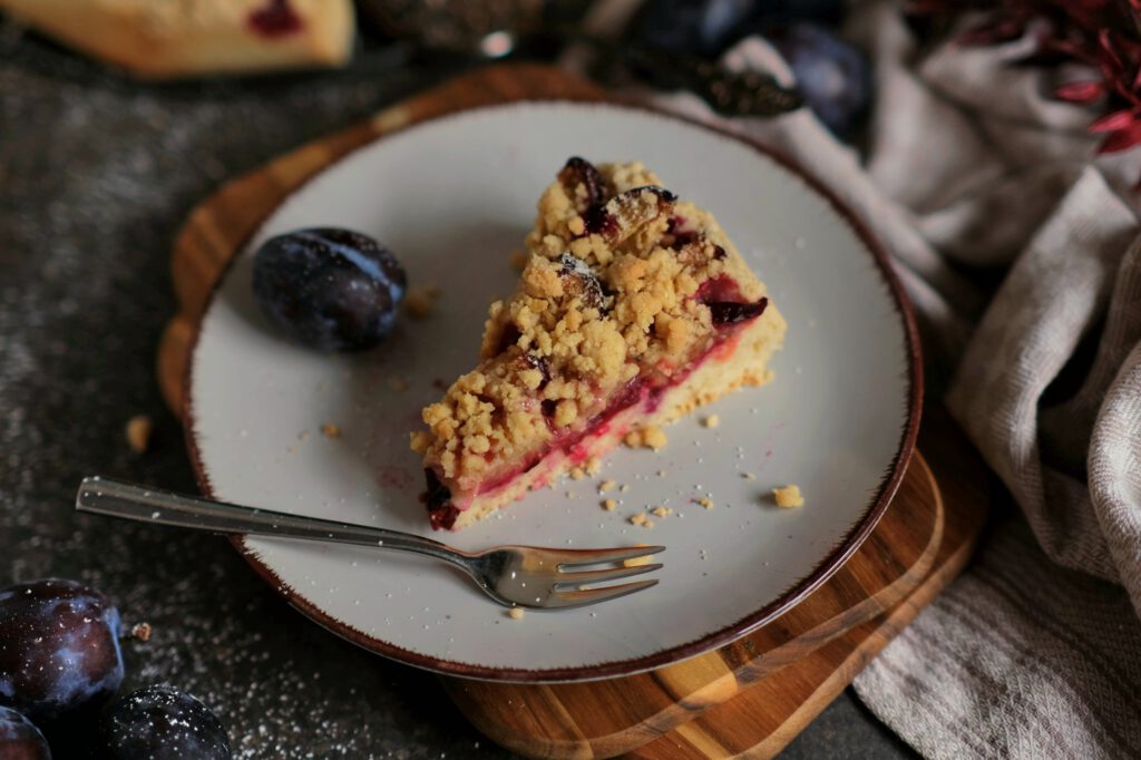 Ein Stück fruchtiger Zwetschgenkuchen vom Quark-Öl-Teig mit knusprigen Streuseln auf einem Dessertteller